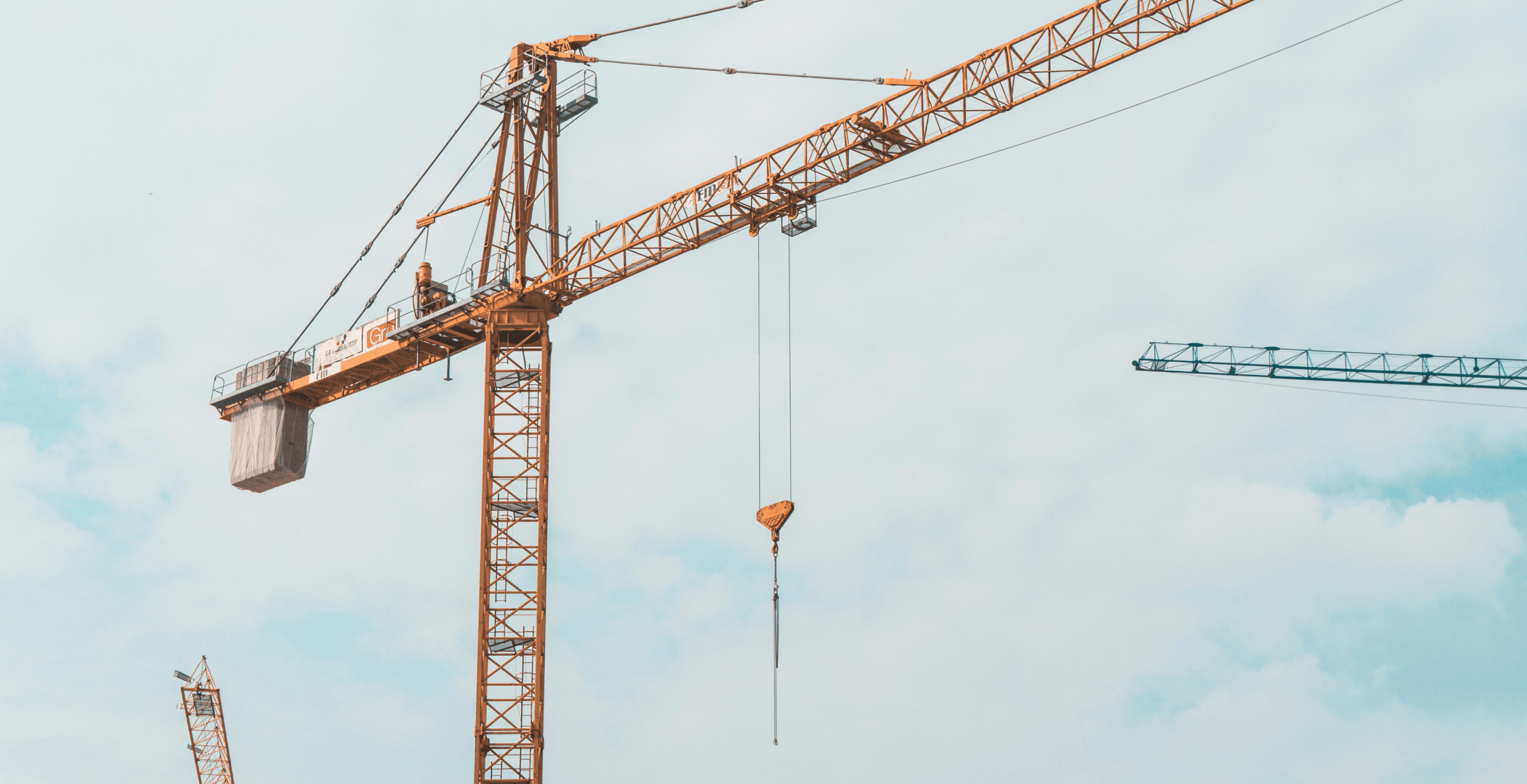 Edifício em construção com gruas contra um céu claro, evocando construção sustentável e responsável